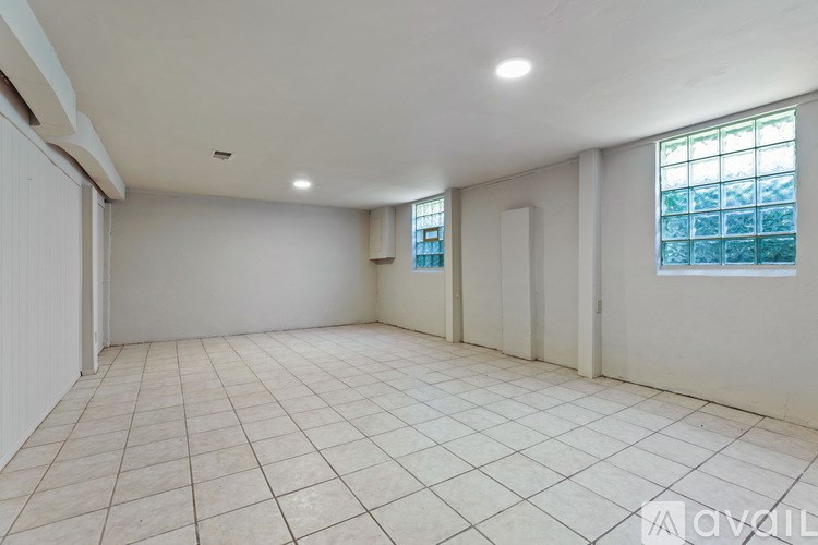A spacious room with tiled flooring and a window on the right wall.