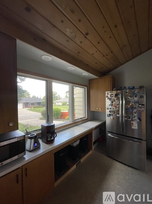A kitchen with wooden cabinets and a stainless steel refrigerator.