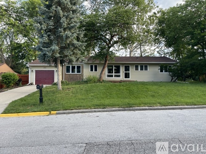 A house with a red garage door is surrounded by greenery.