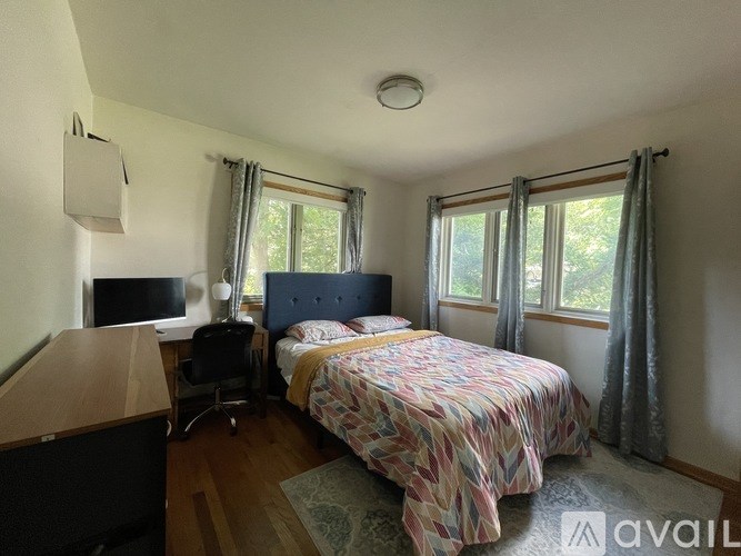 A bedroom with a bed, a desk, and a chair.