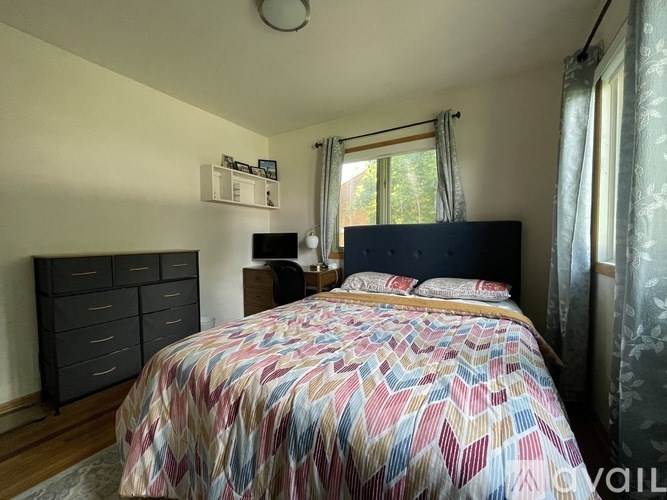 A bedroom with a large bed and a window with curtains.