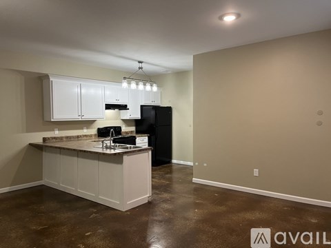 A kitchen with brown floors and white cabinets is available.