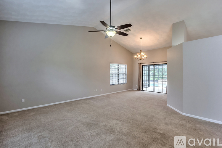 A spacious room with a ceiling fan and a chandelier.
