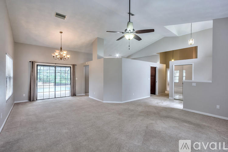 A spacious living room with a ceiling fan and a chandelier.