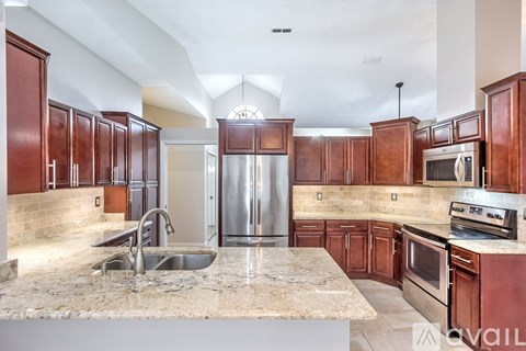 A kitchen with brown cabinets and a marble countertop.