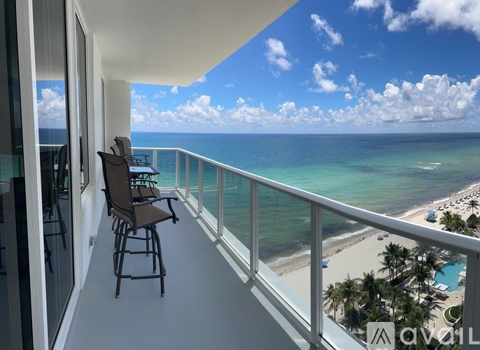 A balcony with chairs overlooking the ocean.