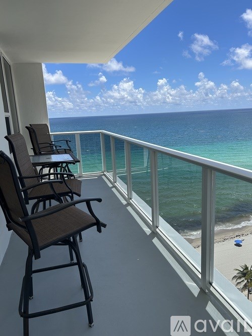 Two chairs are on a balcony overlooking the ocean.