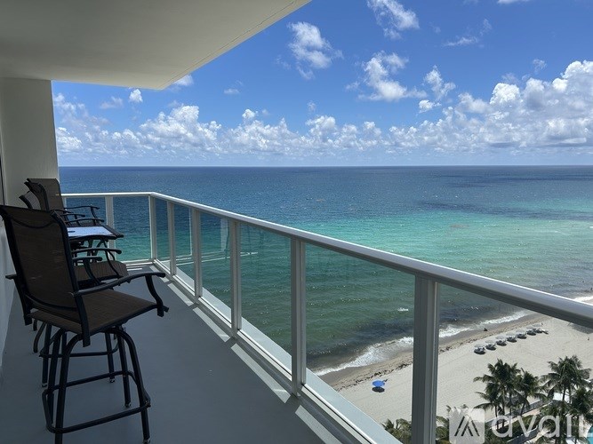 A balcony with a chair and a view of the ocean.