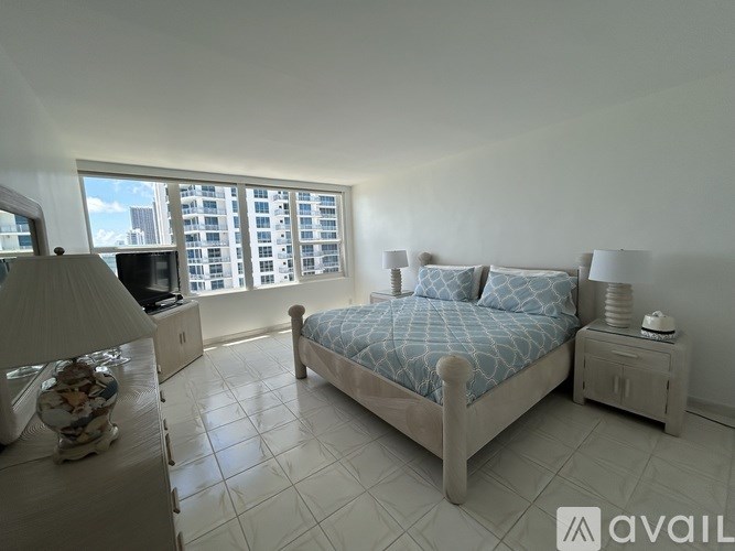A bedroom with a large bed and a window overlooking a cityscape.