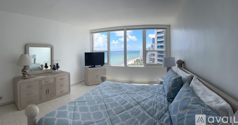 A bedroom with a large bed, a dresser, and a television.