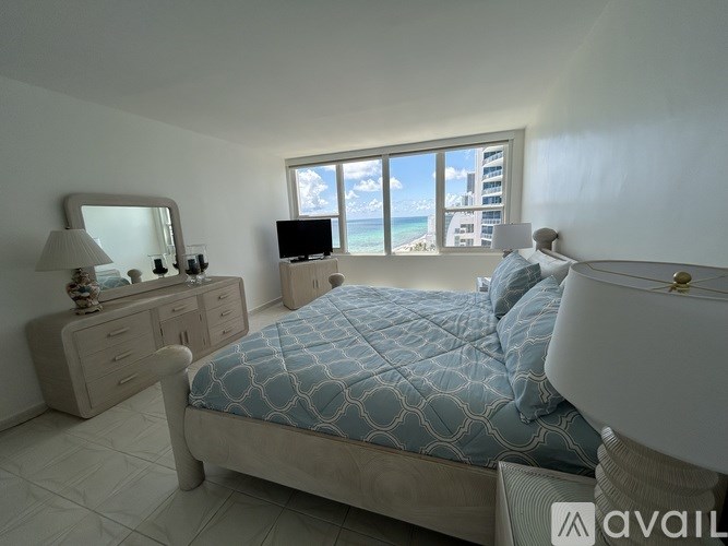 A bedroom with a large bed, a dresser, and a television.