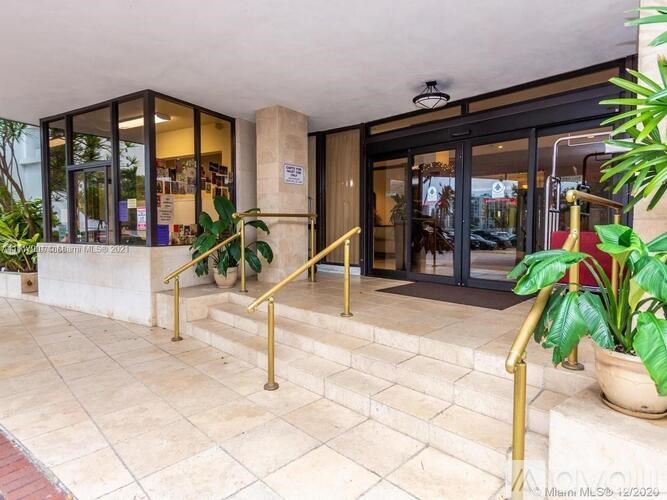 A building entrance with a glass door and a plant on the steps.