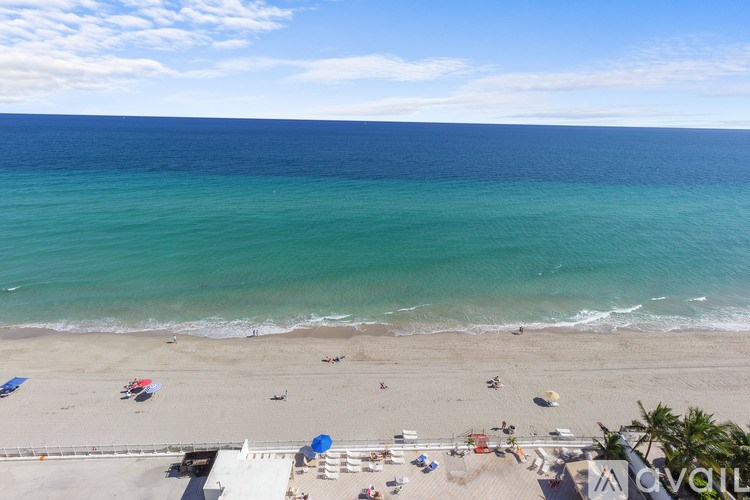 A beach with people and umbrellas on the sand.