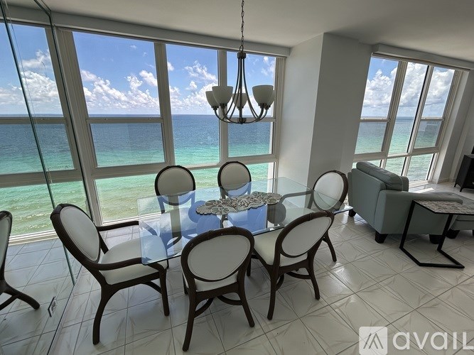 A dining room with a table set for four and a view of the ocean.