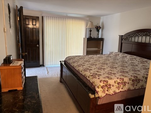 A bedroom with a large bed and a wooden dresser.