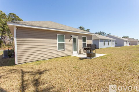 A small house with a brown roof and a white door is surrounded by a grassy area.