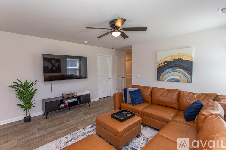 A living room with a brown leather couch and a ceiling fan.