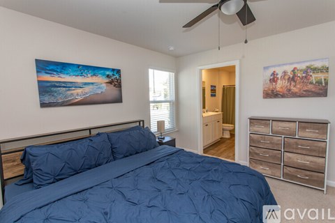 A bedroom with a large bed and a painting of a beach scene on the wall.