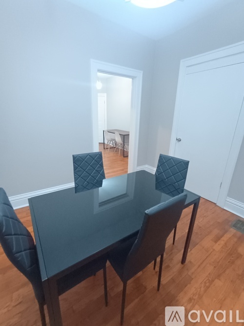A dining room with a glass table and four chairs.