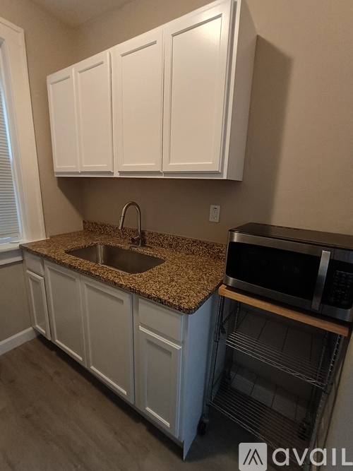 A kitchen with white cabinets and a granite countertop.