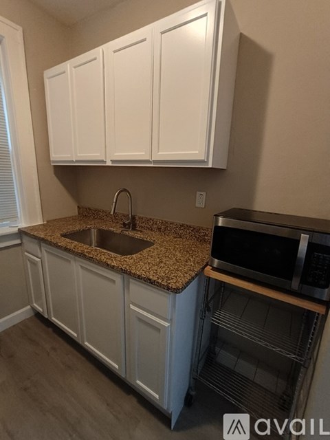A kitchen with white cabinets and a granite countertop.