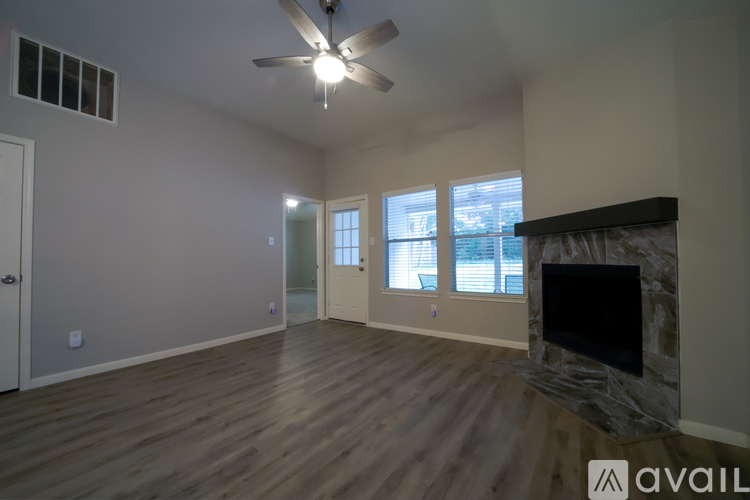 A spacious living room with a fireplace and a ceiling fan.