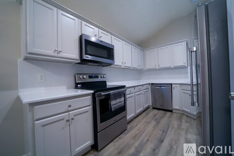 A kitchen with white cabinets and a black microwave above the stove.