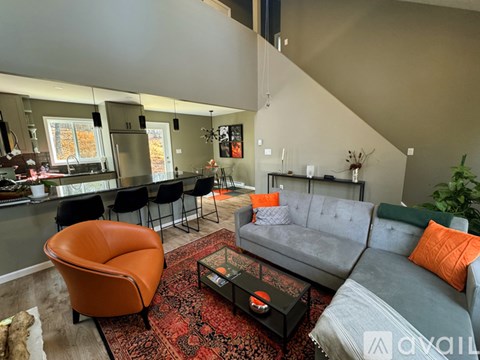 A living room with a grey couch and an orange chair.