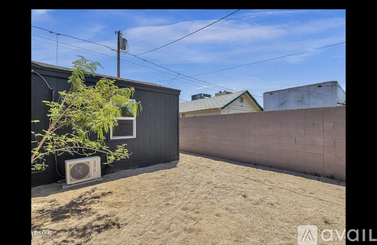 A black building with a tree in front and a wall on the right side.