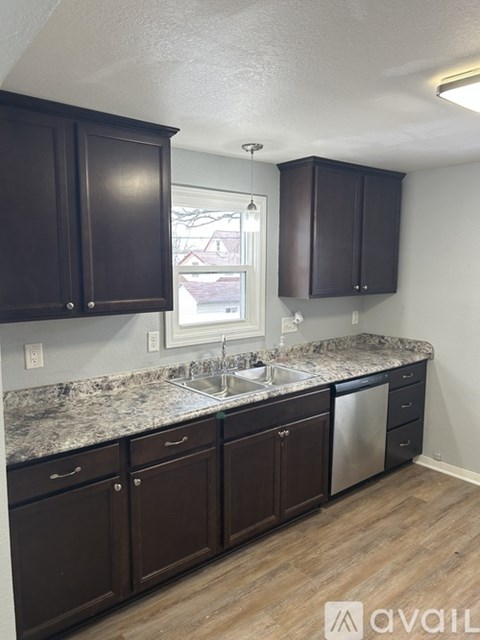 A kitchen with dark brown cabinets and granite countertops.