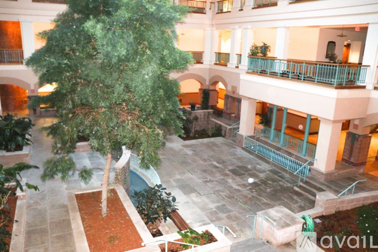 A courtyard with a tree in the middle and a balcony on the right.