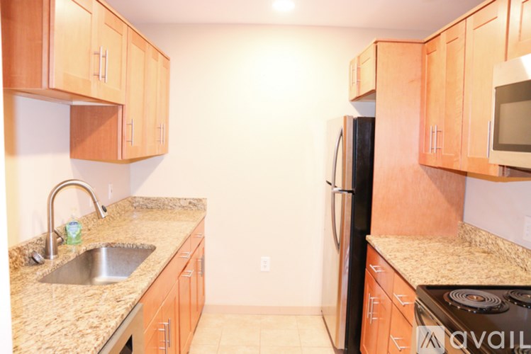 A kitchen with wooden cabinets and a black refrigerator.