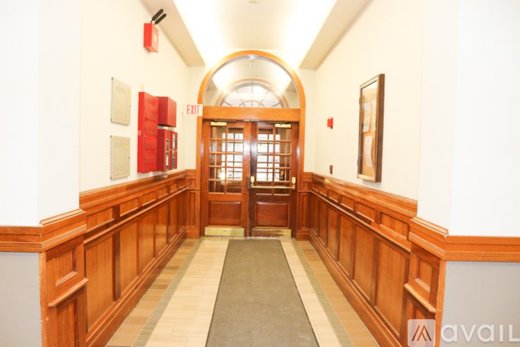 A hallway with a wooden railing and a red door at the end.
