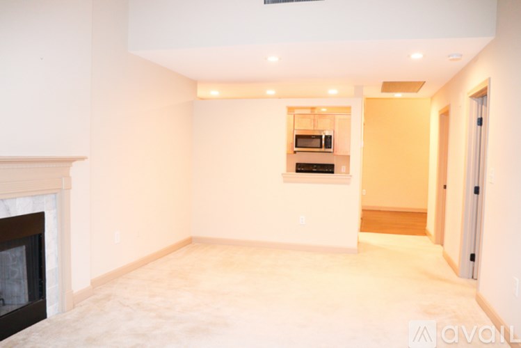 A spacious living room with a fireplace and a kitchen in the background.