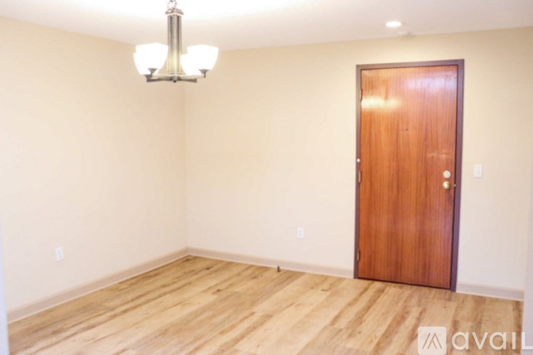 A room with a wooden door and a chandelier hanging from the ceiling.