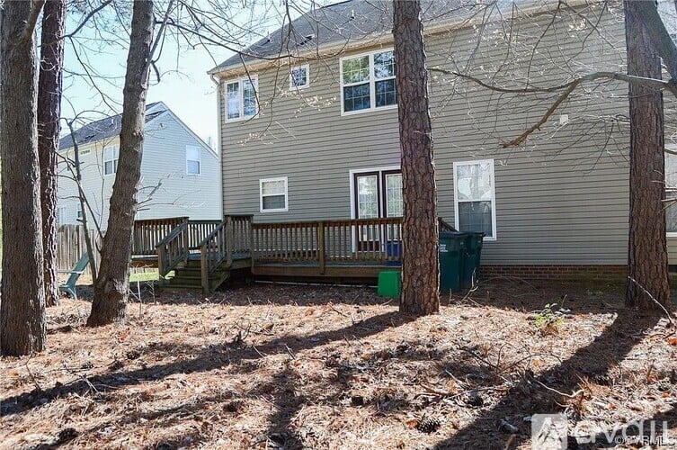 A house with a deck and a tree in front.