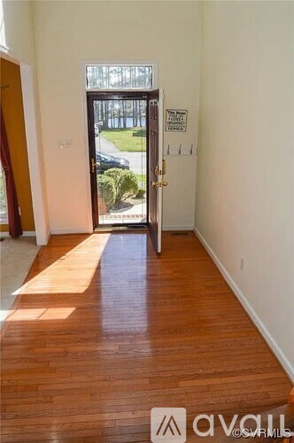 A room with a wooden floor and a door leading outside.
