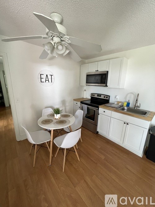 A kitchen with a table and chairs and a sign on the wall that says "EAT".