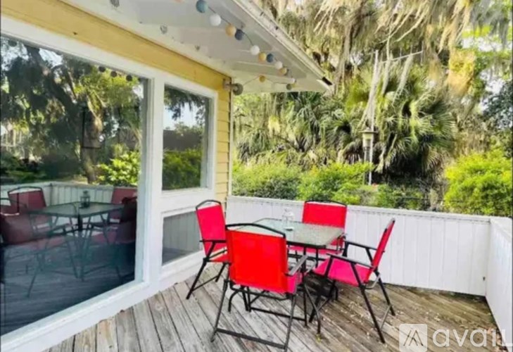 A patio with a table and chairs is set up on a wooden deck.