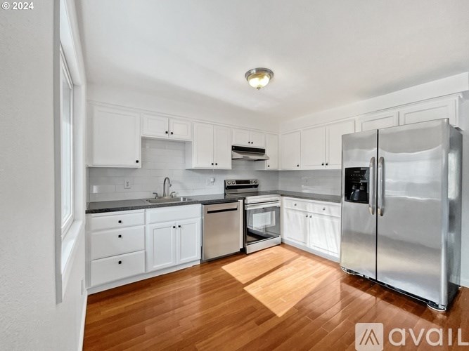 A kitchen with white cabinets and a wooden floor.
