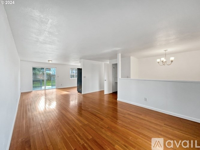 A spacious room with wooden flooring and white walls.