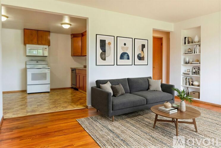 A room with wooden floors and a window showing trees outside.