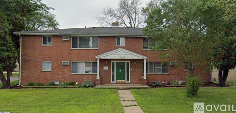 A red brick house with a green door and a white window.