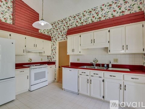 A kitchen with white cabinets and a red backsplash.
