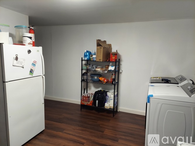 A white refrigerator is in a kitchen with a wooden floor.