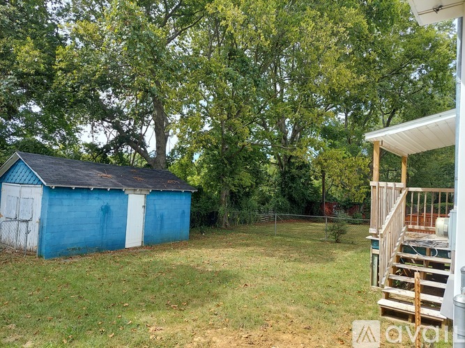 A blue shed sits in a grassy backyard.