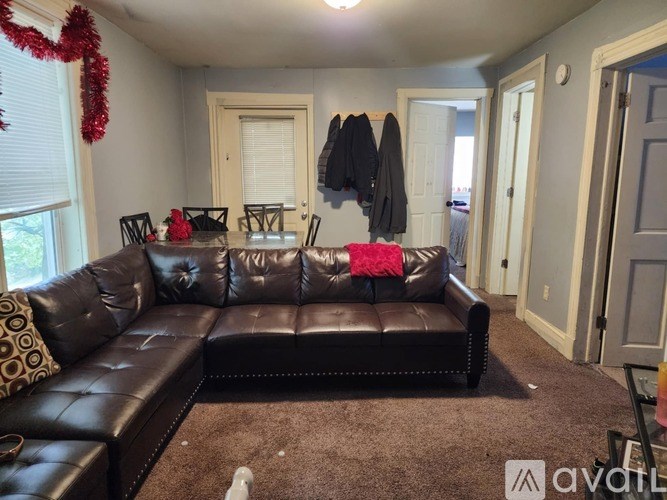 A black leather couch with a red throw on it in a room.