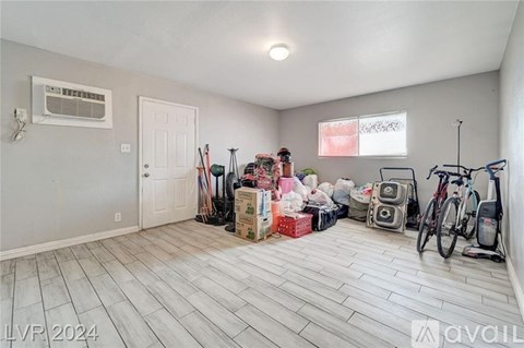 A room with a white door, a bicycle, and a pile of boxes on the floor.
