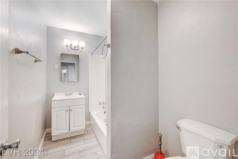 A white bathroom with a tub, sink, and mirror.