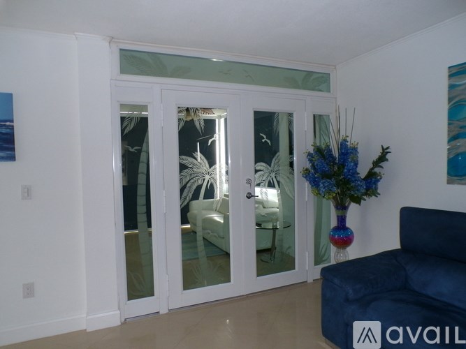 A living room with a blue couch and a vase of flowers on a table.